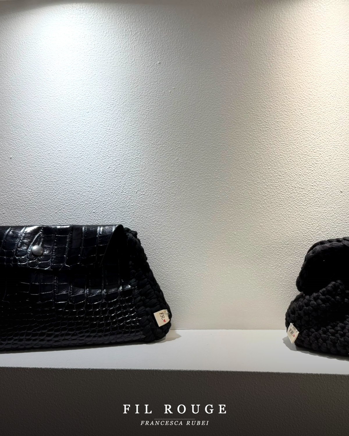 Black croc-effect clutch beside a black knotted crochet bag
